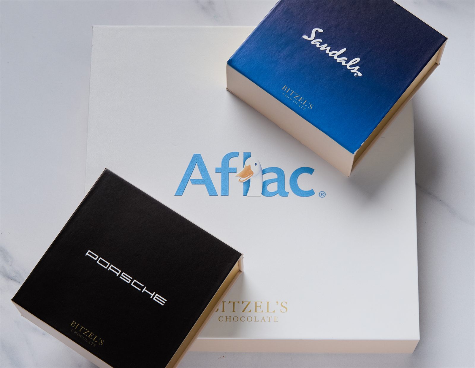 Bitzel's-branded corporate gift boxes for Aflac, Sandals, and Porsche